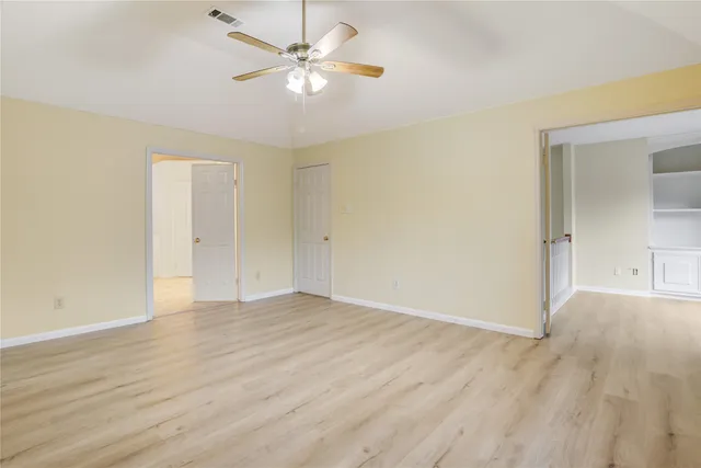 an empty room with wooden floor and windows