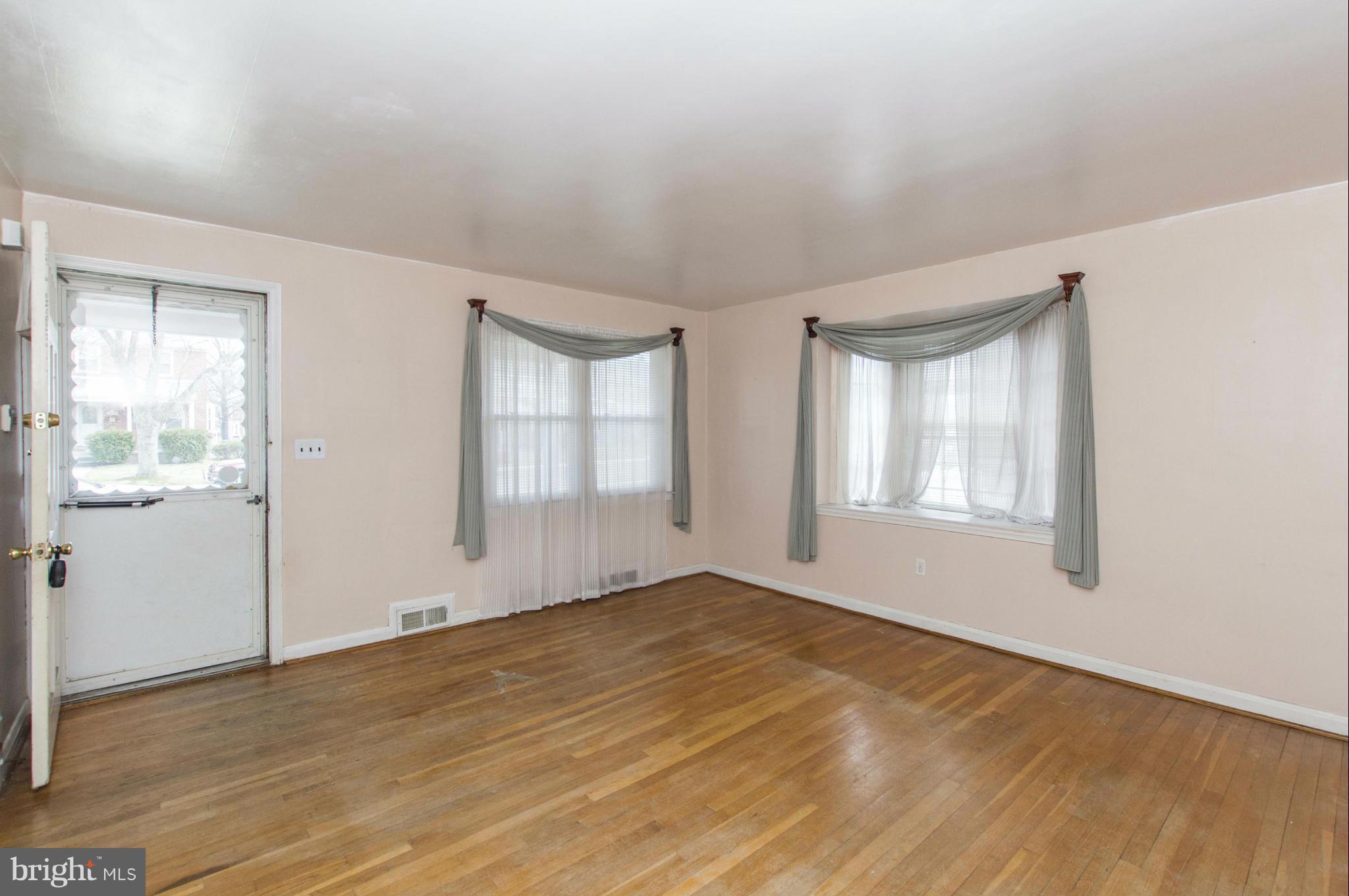 1254 Cedarcroft Road Baltimore, MD 21239 - Photo 3 of 30 an empty room with wooden floor and windows