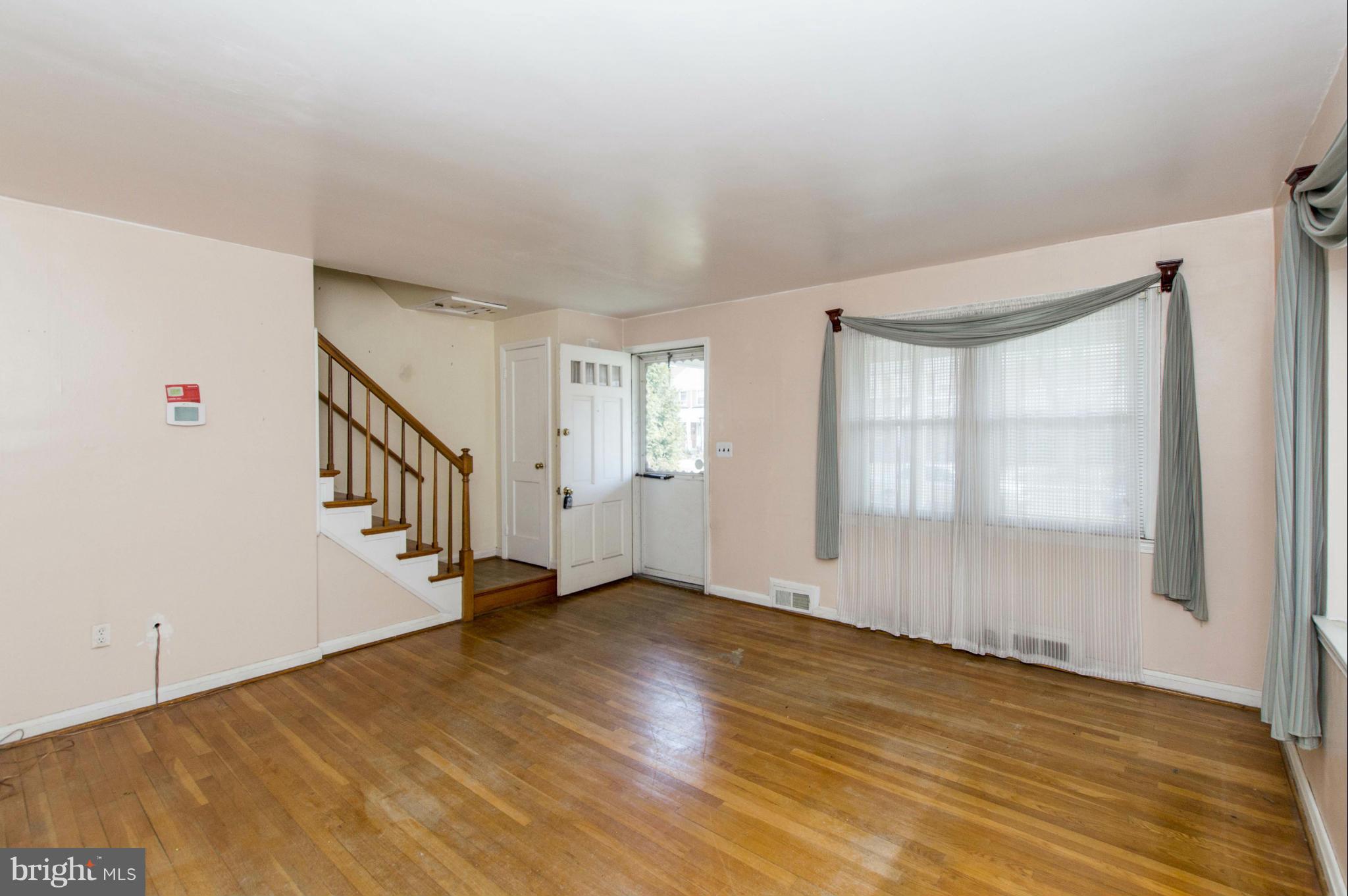 1254 Cedarcroft Road Baltimore, MD 21239 - Photo 6 of 30 a view of an empty room with wooden floor and windows