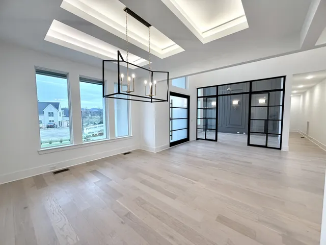 an empty room with wooden floor and windows with curtains