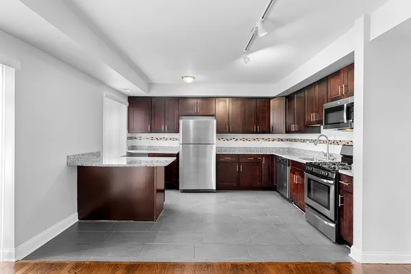 a kitchen with stainless steel appliances kitchen island granite countertop a stove refrigerator and cabinets