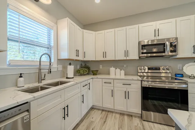 a kitchen with stainless steel appliances granite countertop a stove a sink dishwasher and a microwave oven with white cabinets