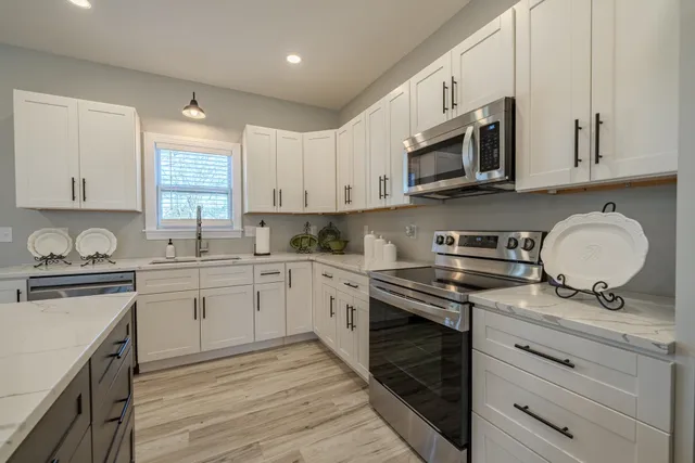 a large kitchen with stainless steel appliances kitchen island granite countertop a large counter top a stove a chimney a sink and a refrigerator