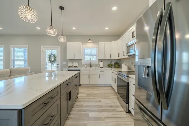 a kitchen with a dining table chairs wooden floor cabinets and stainless steel appliances