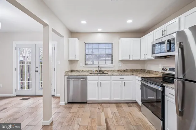 a kitchen with stainless steel appliances granite countertop a stove top oven a sink and a refrigerator