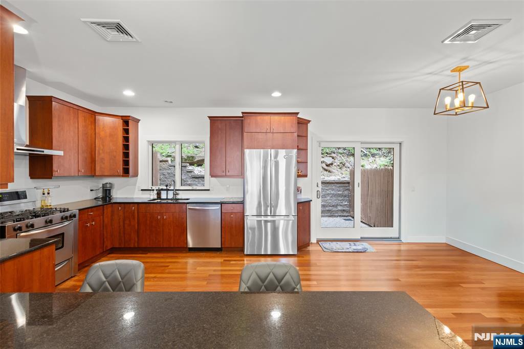 7 Oakdene Terrace, Unit 7 Edgewater, NJ 07020 - Photo 12 of 30 a kitchen with stainless steel appliances granite countertop a refrigerator a stove and a sink with wooden floor
