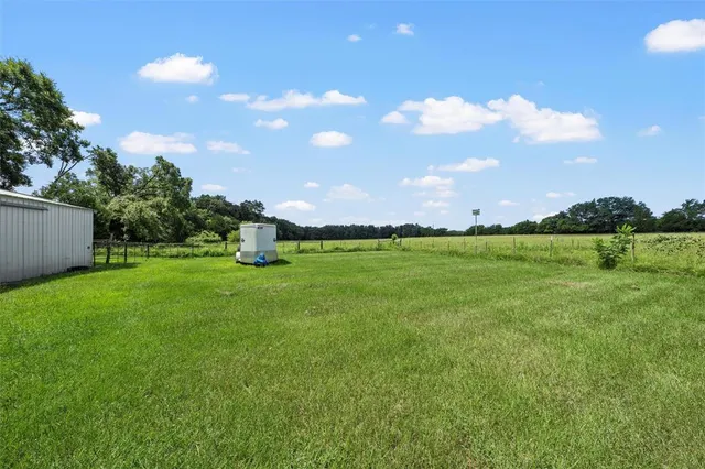 a backyard of a house with wooden fence and large trees