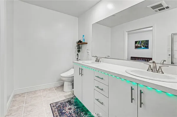a bathroom with a double vanity sink toilet and a mirror