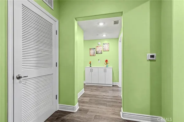 a view of a hallway with wooden floor and a bathroom