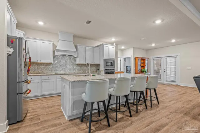 a kitchen with stainless steel appliances granite countertop a stove a sink a refrigerator and a dining table with wooden floor