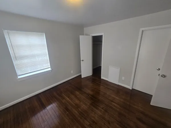 a view of an empty room with wooden floor and a window