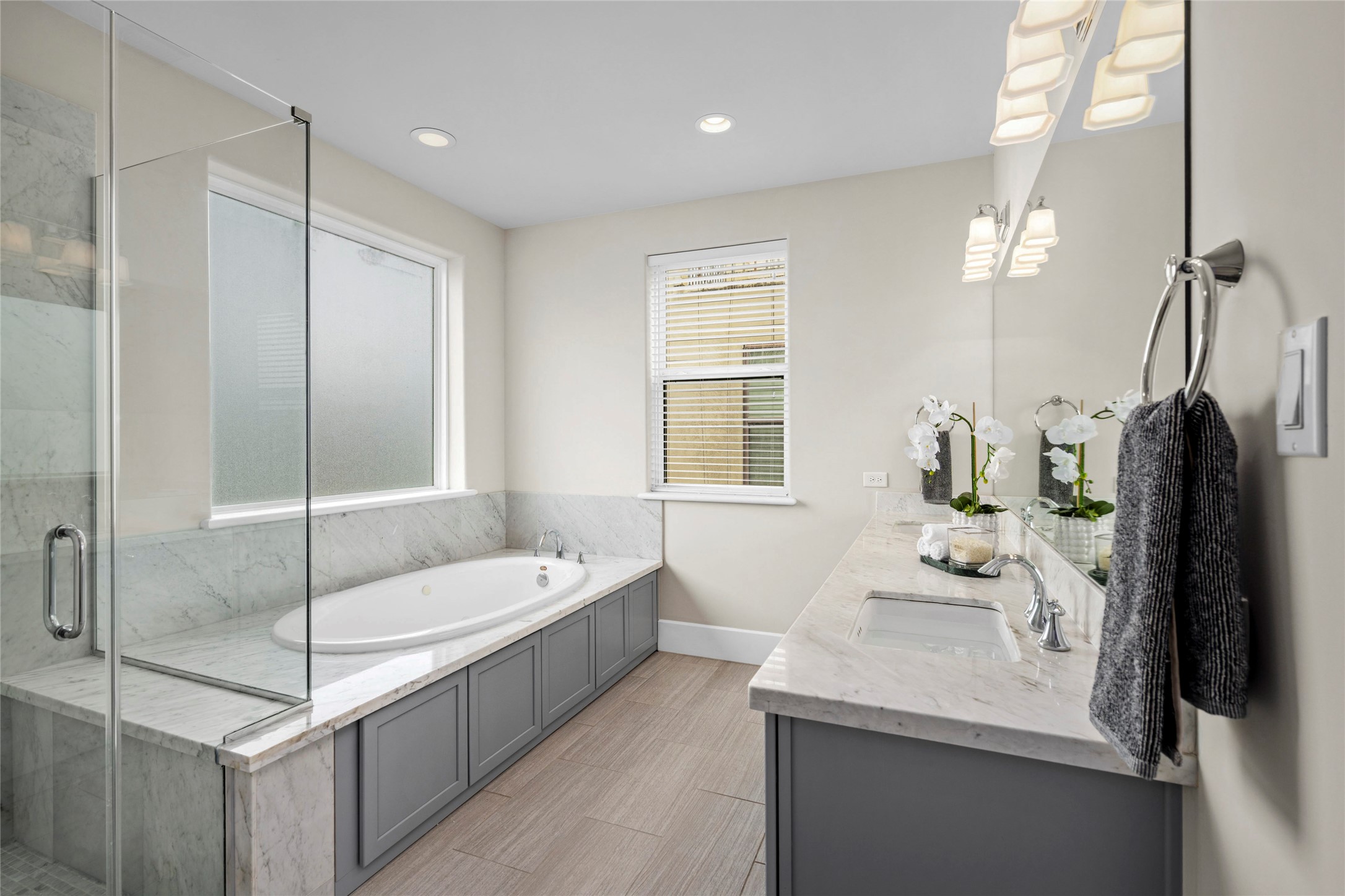 5646 Larkin Street Houston, TX 77007 - Photo 11 of 29 A bright primary bath with marble finishes, dual sinks, a soaking tub, and a glass-enclosed shower.