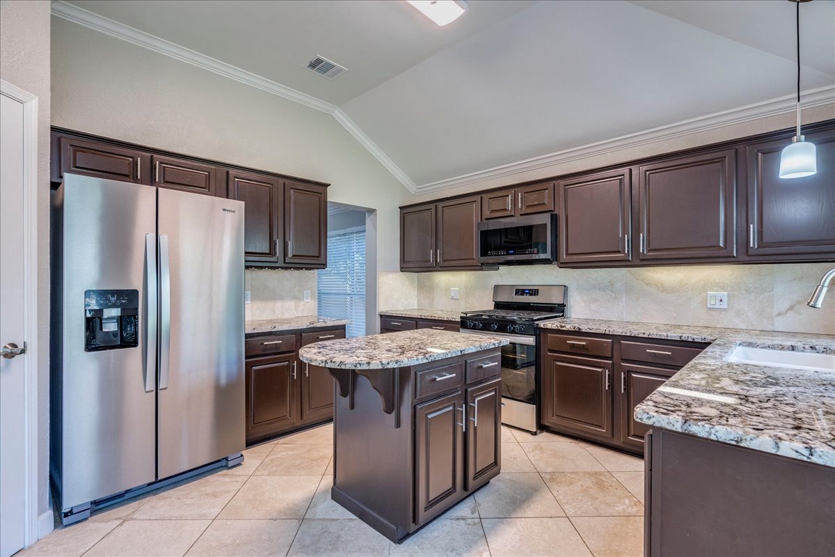 6530 Needham Lane Austin, TX 78739 - Photo 10 of 29 Culinary dreams come alive in this kitchen featuring an island with granite counters and rich cabinetry.