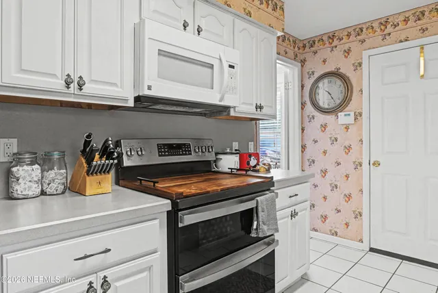 a kitchen with granite countertop white cabinets and stainless steel appliances