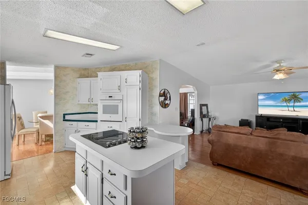 a large white kitchen with stainless steel appliances granite countertop a lot of counter space and a couch