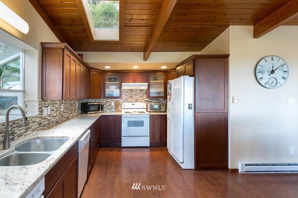 744 Miller Road Sequim, WA 98382 - Photo 19 of 40 a kitchen with stainless steel appliances granite countertop a sink a refrigerator a washer and dryer with wooden floors