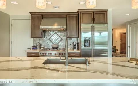 a kitchen with kitchen island granite countertop a stove a sink and a dining table with chairs