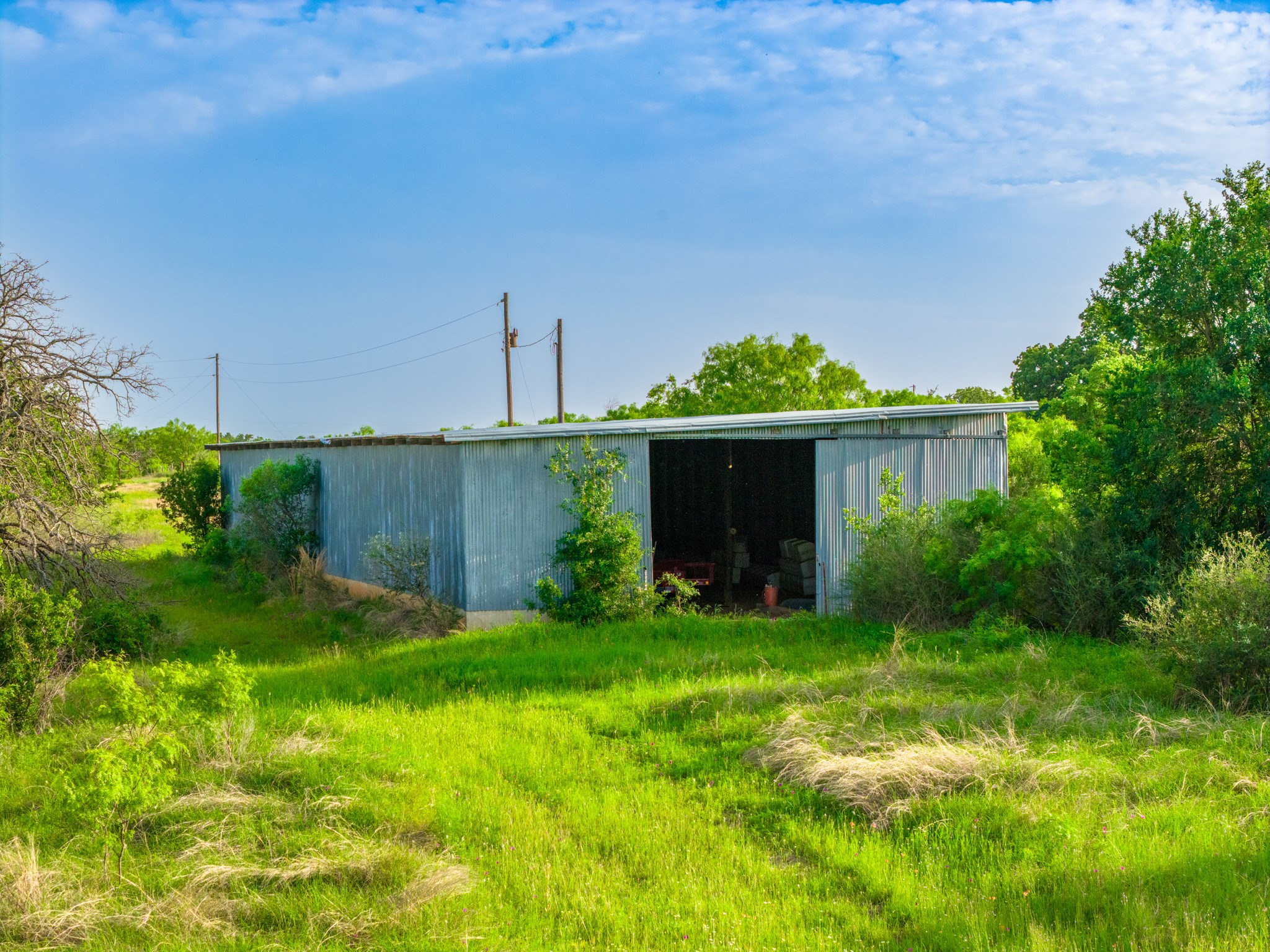 11079 Cr 266 Rochelle Tx 76872 Rochelle, TX 76872 - Photo 32 of 40 Corrugated metal outbuilding with an open bay and surrounding green landscape