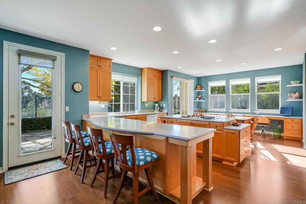 8046 Calle Pinon Carlsbad, CA 92009 - Photo 16 of 51 a dining room with stainless steel appliances granite countertop a table and chairs with wooden floor