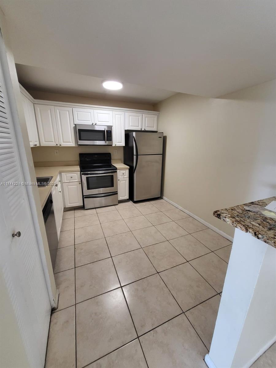 711 North Pine Island Road, Unit 407 Plantation, FL 33324 - Photo 2 of 11 a kitchen with a stove top oven and cabinets
