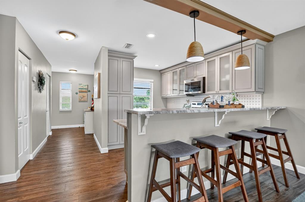 a kitchen with stainless steel appliances kitchen island granite countertop a table chairs refrigerator and microwave