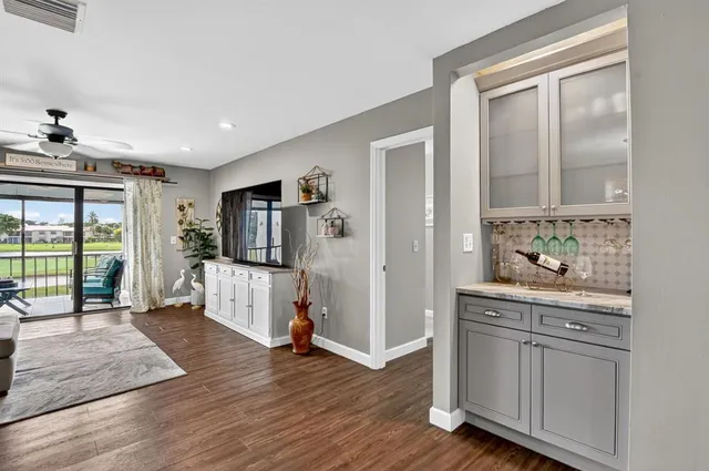 a living room with stainless steel appliances kitchen island granite countertop a refrigerator a sink a stove and cabinets with wooden floor