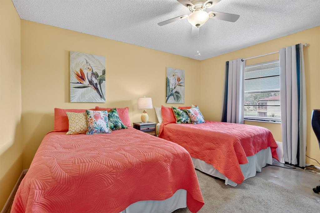 21219 Lago Circle, Unit J5 Boca Raton, FL 33433 - Photo 27 of 46 a bedroom with two beds and a chandelier