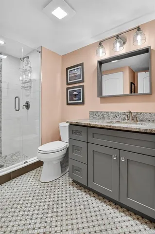 a bathroom with a granite countertop sink a toilet a mirror and shower