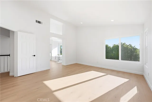 an empty room with wooden floor and windows