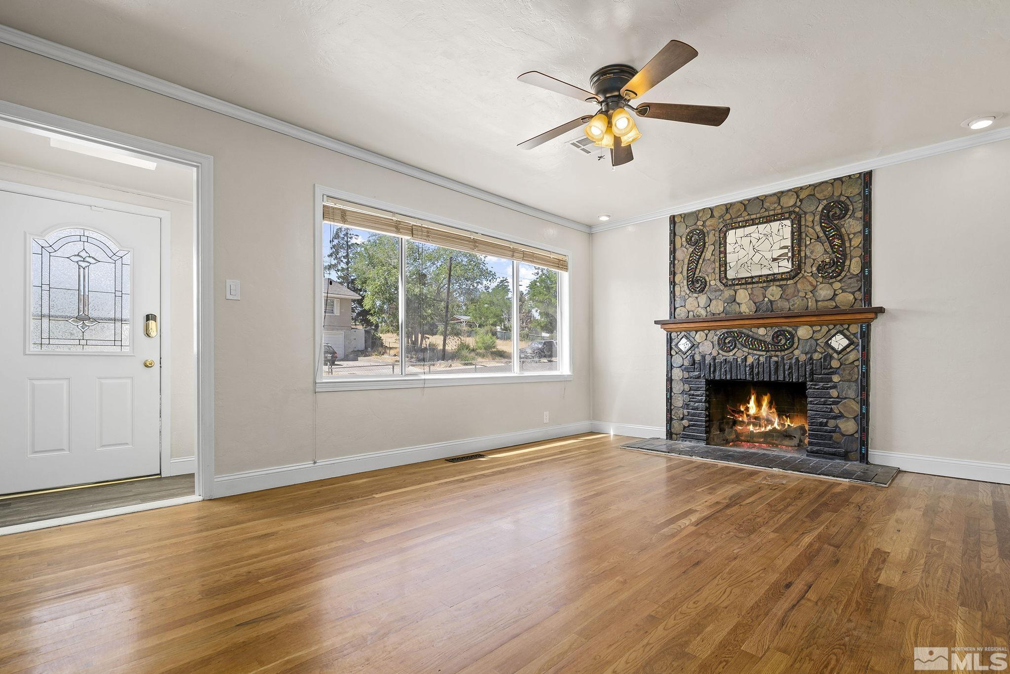 1445 University Terrace Reno, NV 89503 - Photo 5 of 17 an empty room with windows a fireplace a ceiling fan and wooden floor