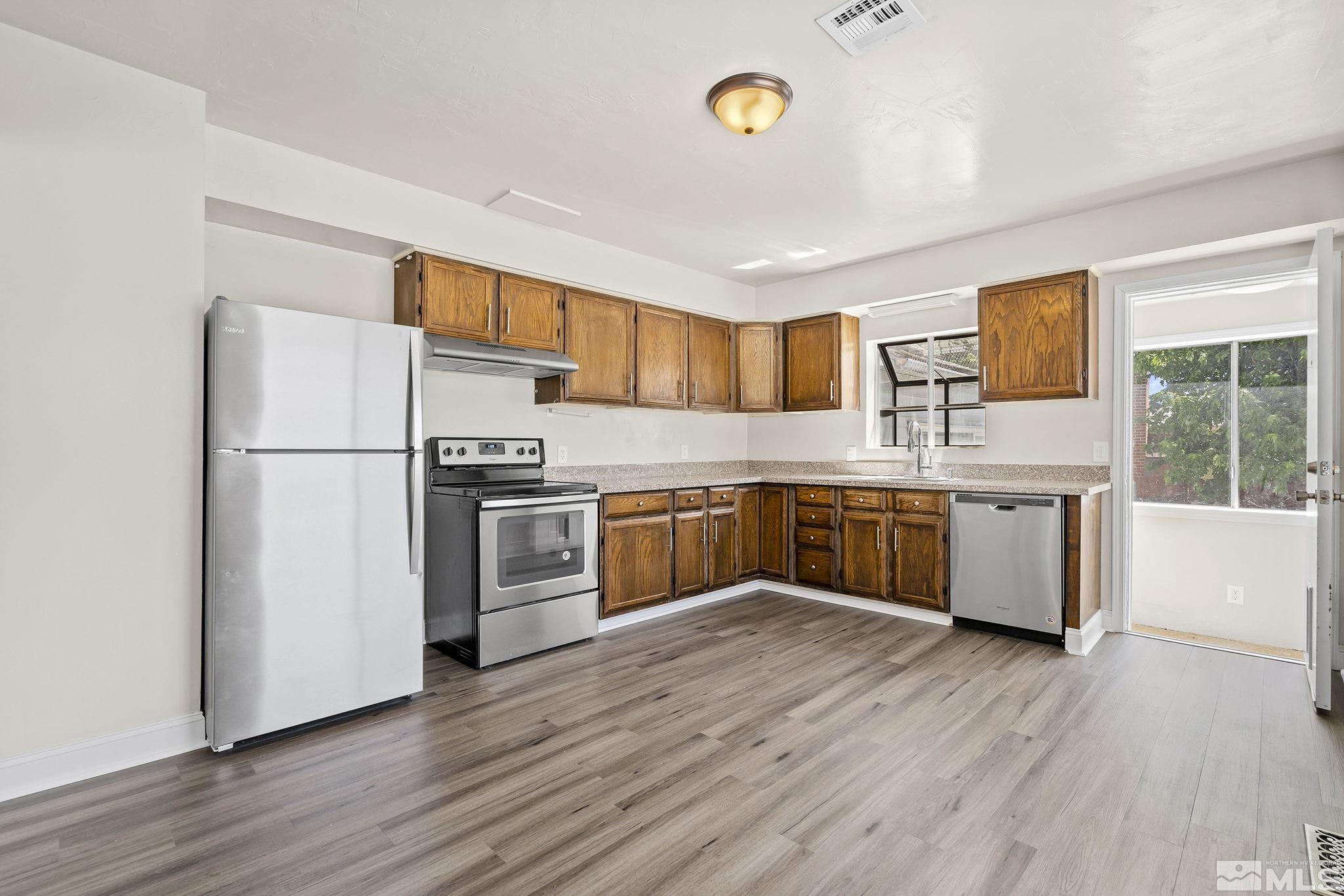 1445 University Terrace Reno, NV 89503 - Photo 6 of 17 a kitchen with stainless steel appliances granite countertop a sink a stove a refrigerator cabinets and a wooden floor