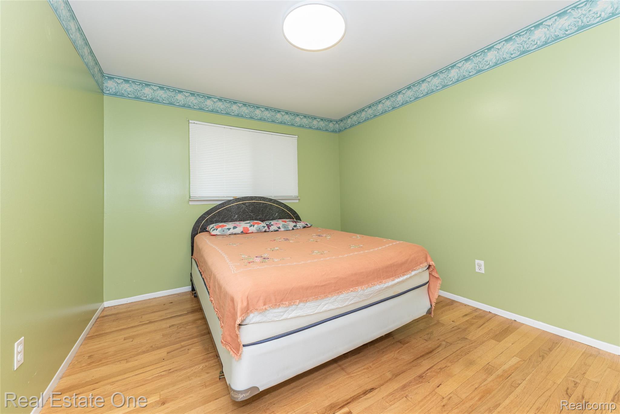 1380 North Sheldon Road Canton, MI 48187 - Photo 21 of 29 Bedroom featuring wood-finish flooring, light green walls with decorative border, a single window with blinds, and a ceiling-mounted light fixture
