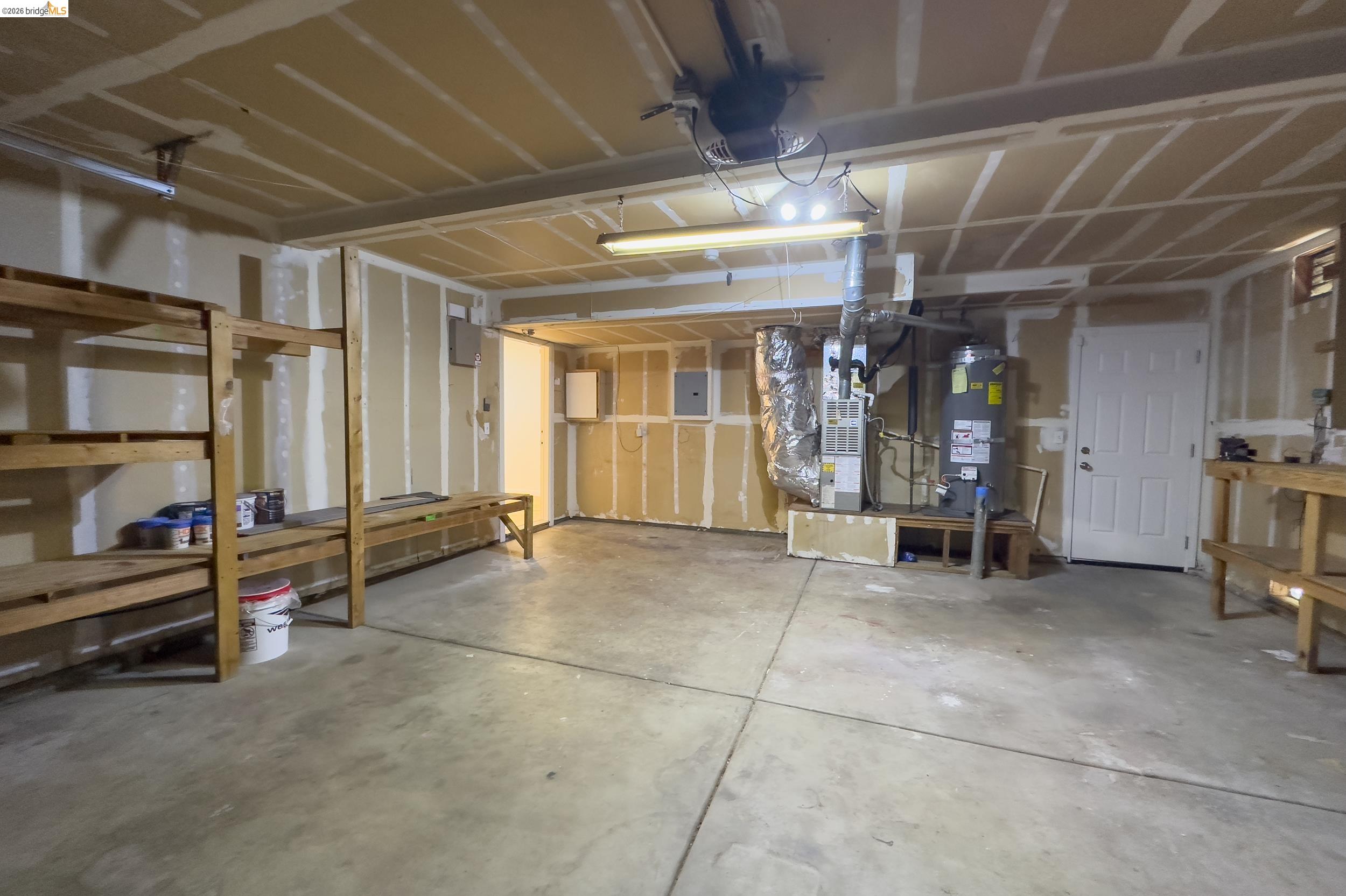 512 Burdick Drive Bay Point, CA 94565 - Photo 50 of 50 Spacious garage featuring concrete flooring, built-in shelving, a white utility door, and exposed utility systems
