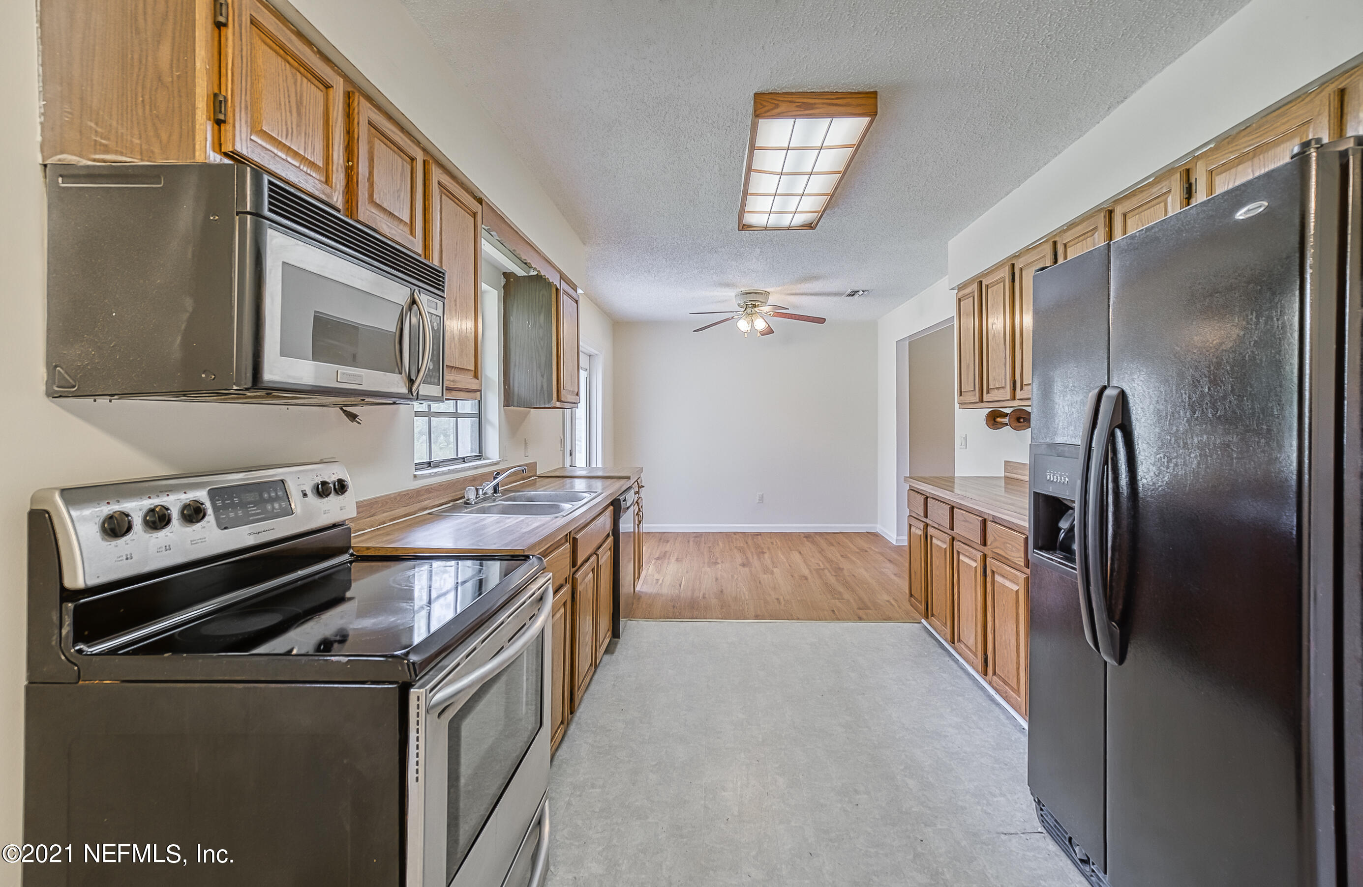 54212 Armstrong Road Callahan, FL 32011 - Photo 13 of 47 a kitchen with stainless steel appliances granite countertop a refrigerator a stove and a sink with wooden floor