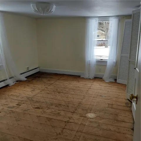 a view of hallway with window and wooden floor