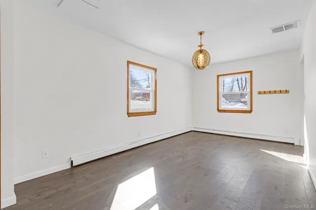 a view of an empty room with a window and a chandelier fan