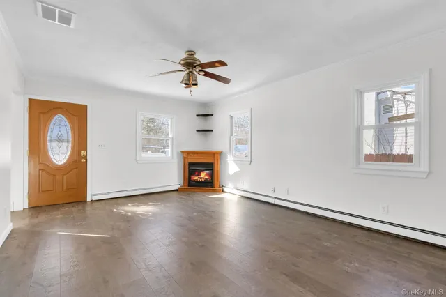 a view of an empty room with wooden floor and window