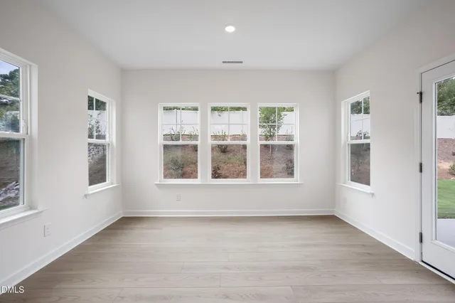 an empty room with wooden floor ceiling fan and windows
