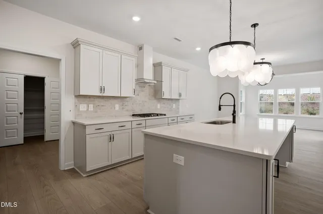a kitchen with kitchen island granite countertop a white cabinets and chandelier