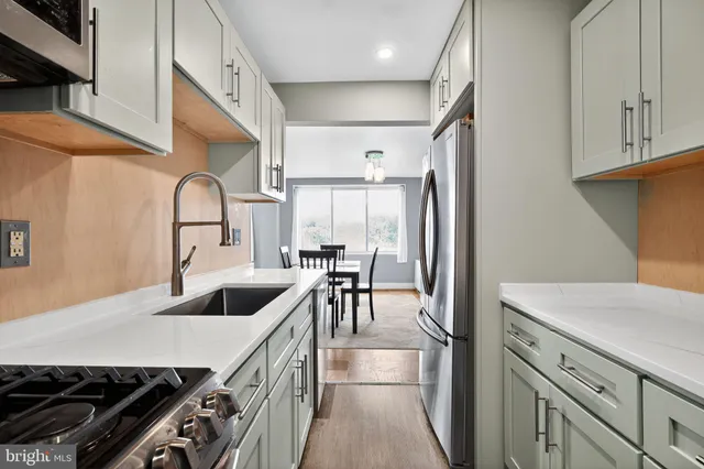 a kitchen with kitchen island a counter top space a sink stainless steel appliances and cabinets