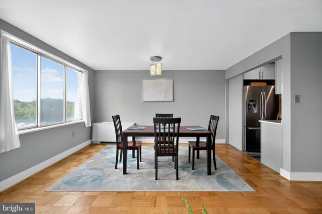 a dining room with furniture a rug a fireplace and a large window