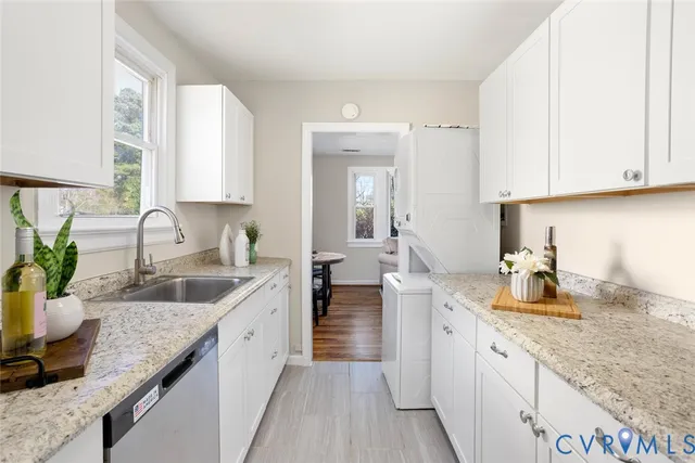 a kitchen with granite countertop a sink and white cabinets
