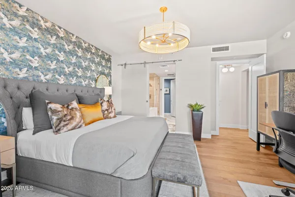 a bedroom with a bed table flowerpot and a chandelier