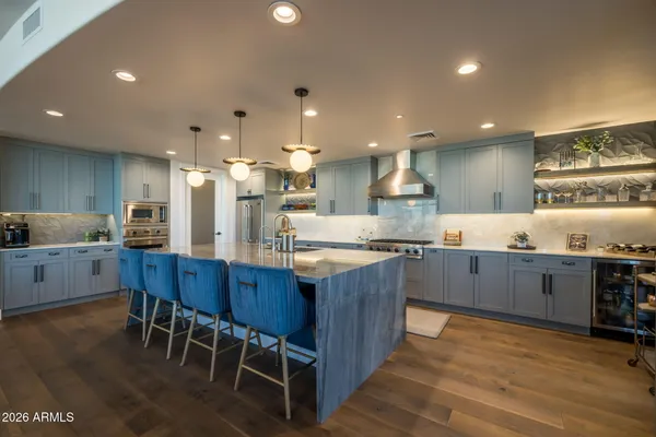 a kitchen with stainless steel appliances kitchen island granite countertop a table chairs sink and cabinets