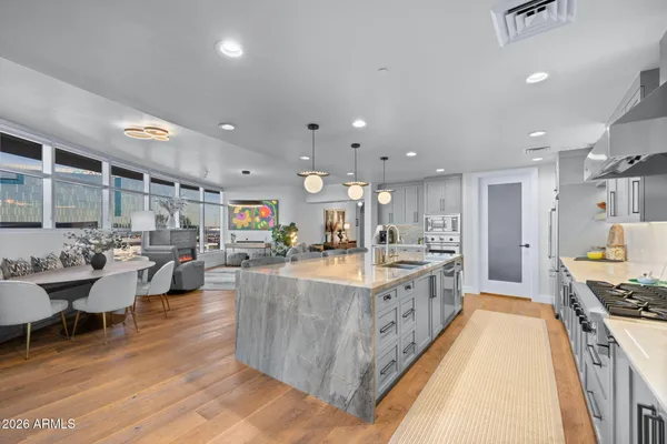 a room with stainless steel appliances kitchen island granite countertop wooden floors and view living room