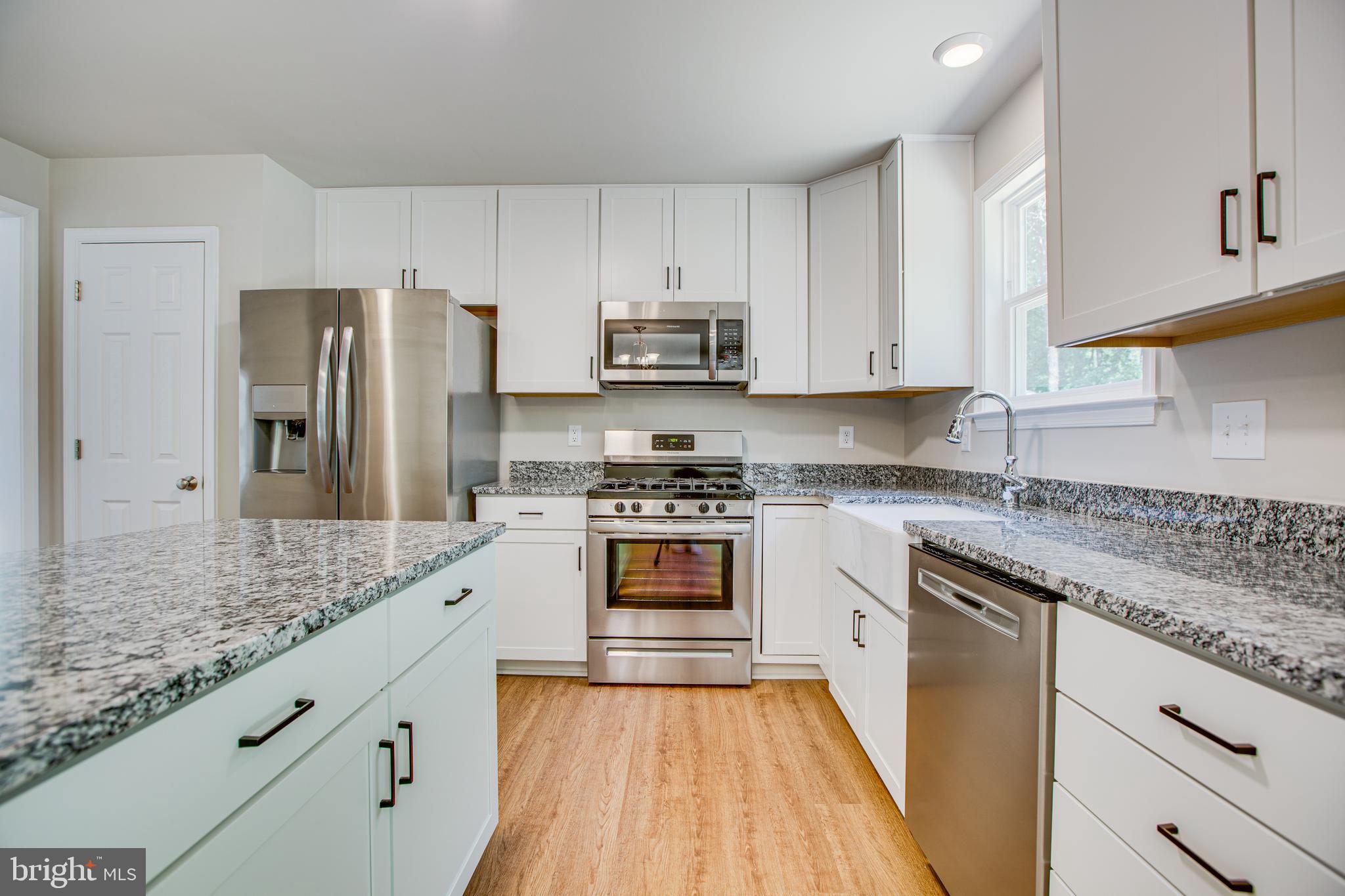 282 Circle Lane Colonial Beach, VA 22443 - Photo 25 of 57 a kitchen with granite countertop a refrigerator stove and sink with wooden floor