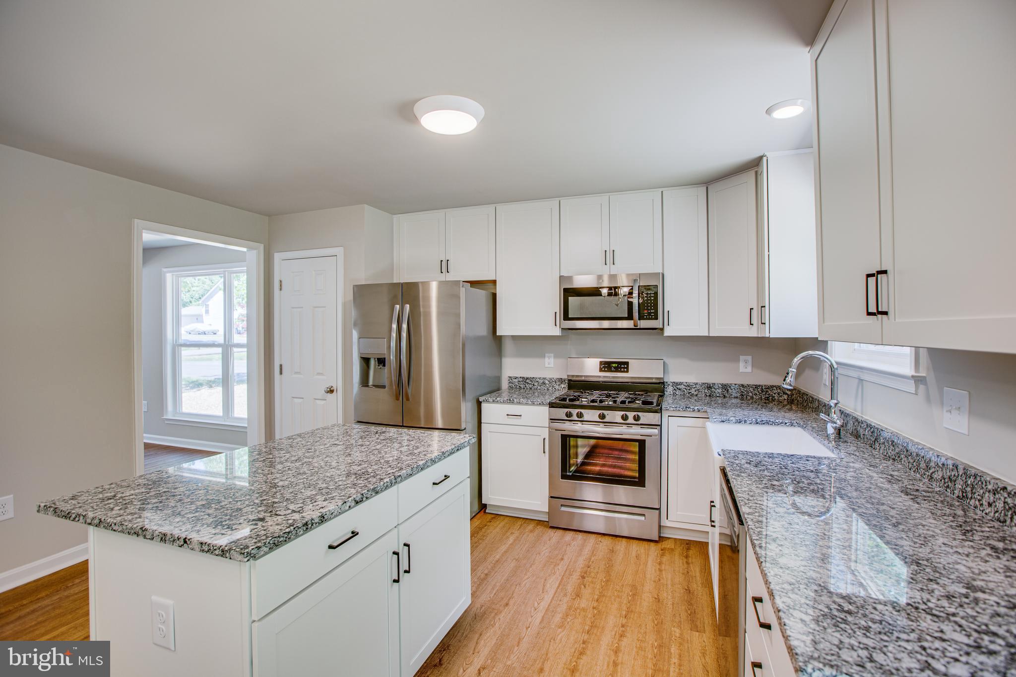 282 Circle Lane Colonial Beach, VA 22443 - Photo 6 of 57 a kitchen with kitchen island granite countertop a stove a sink a refrigerator and white cabinets with wooden floor
