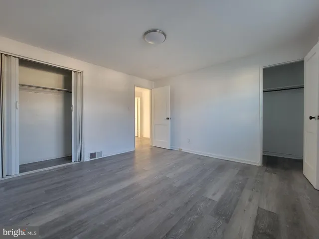 an empty room with wooden floor & closet area