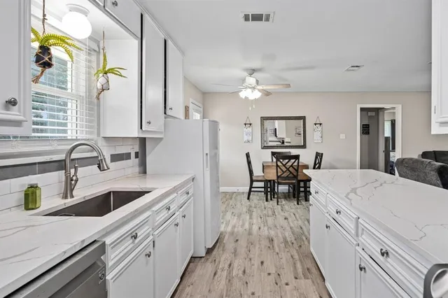 a large white kitchen with a stove a sink a dining table and chairs