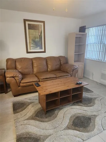 a living room with furniture a wall paintings and a window